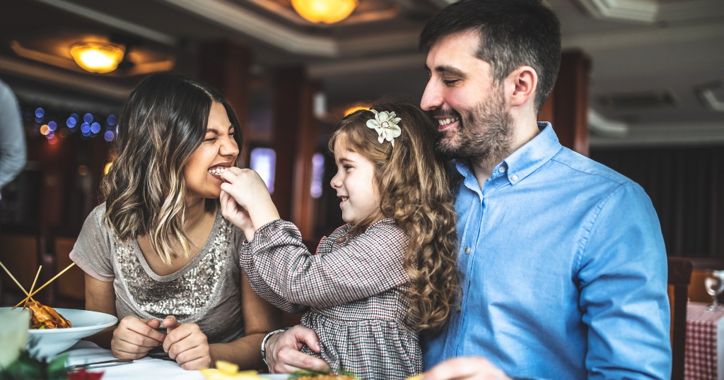 Couple enjoying a meal with their child at a restaurant