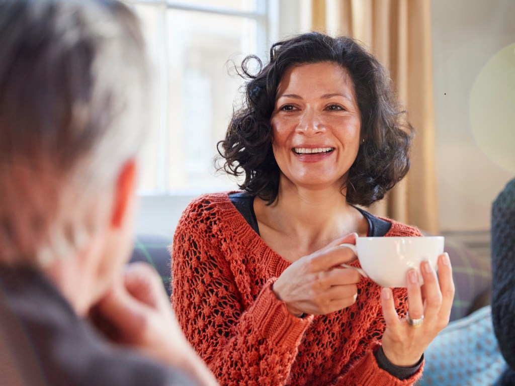 Woman drinking coffee or tea and smiling with friends