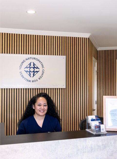 Feature photo - female healthcare assistant sits front of house at Young Naturopathic Wellness Centre 1